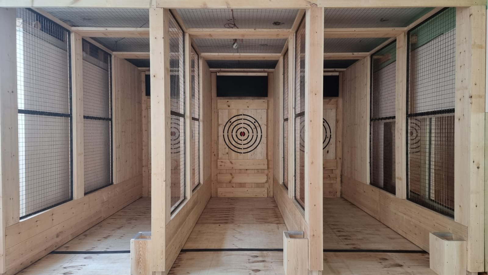 Timber axe throwing lanes with mesh divisions and traditional target faces