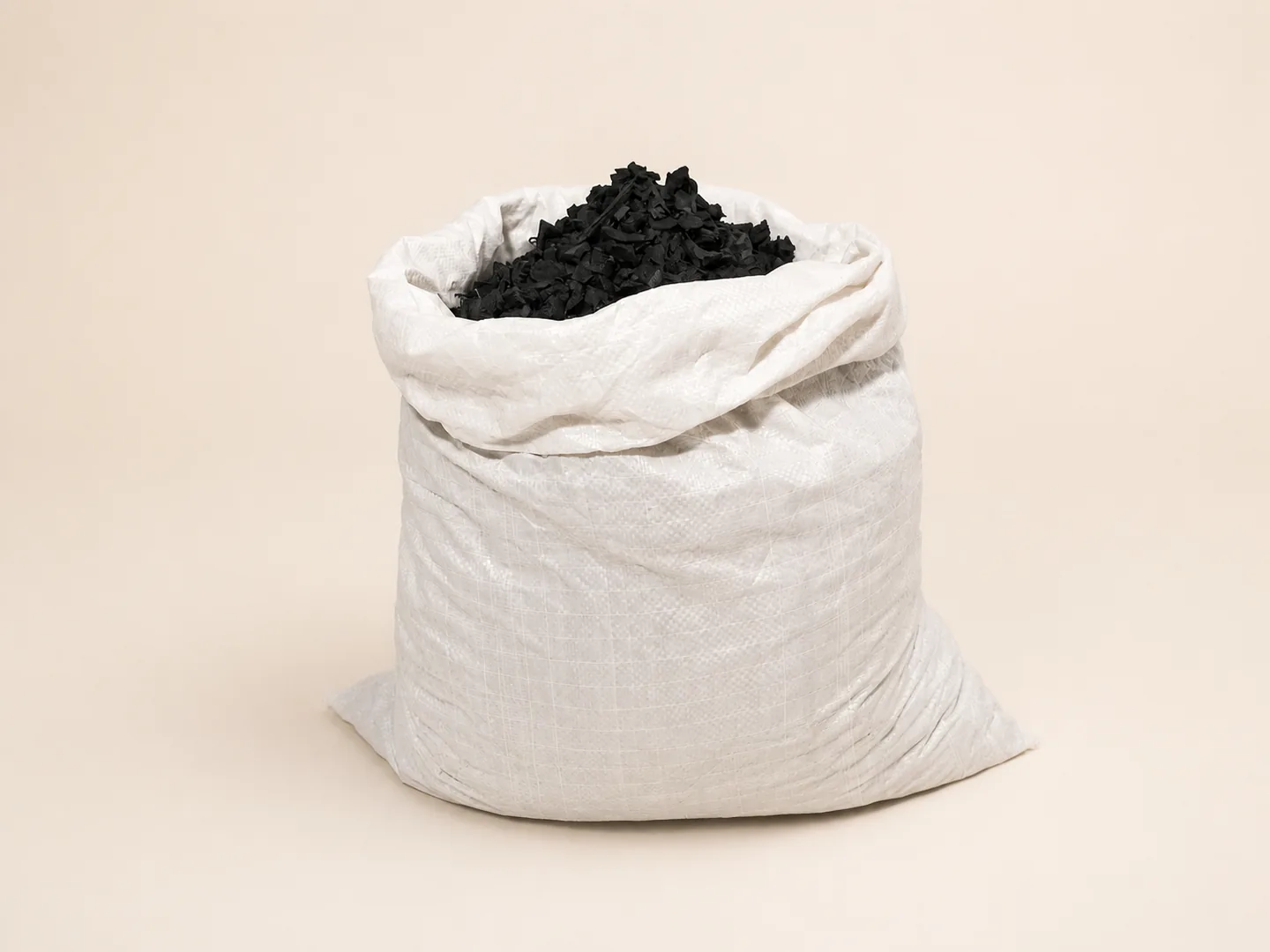 Sack of black rubber chips on ivory
